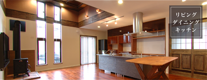 細長い窓に並んだ煙突がある薪ストーブ。空調は柔らかくて温かい空気を各部屋へ送ります。 採光を考慮した明るく開放的なリビングとアイランド型のキッチン。 リビングの雰囲気に合せて作られたオリジナルの食器棚は抜群の収納力を誇ります。