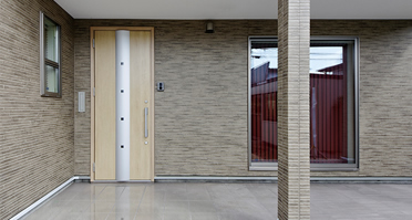 モダンな玄関ドア、玄関横のリビング窓からは四季折々の庭木を楽しんでいただけます。