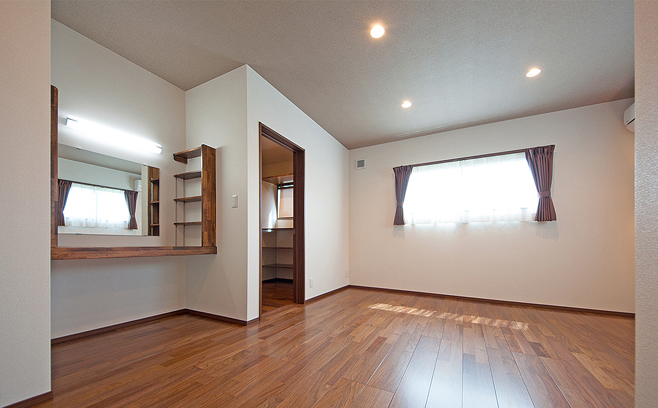 ドレッサーとウォークインクローゼットのある寝室